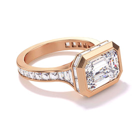shield bezel set east west emerald cut engagement ring with baguette diamond halo and band in 18k rose gold