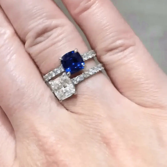 Bespoke Sapphire & Diamond Toi Et Moi Engagement Ring worn on a finger, one with a blue sapphire and one with a square diamond.