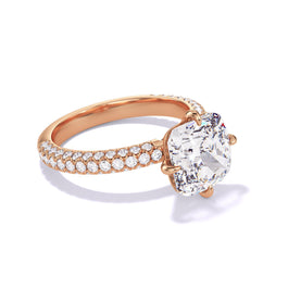 An angled view of Lindsey Scoggins Studio’s Cushion Cut Diamond Engagement Ring With a Compass 4 Prong Three Phases Triple Pave Setting in 18K Rose Gold.