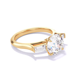 An angled view of an 18K Yellow Gold Round Cut Diamond Engagement Ring with a Baguette Flank Three Phases Slim Setting.