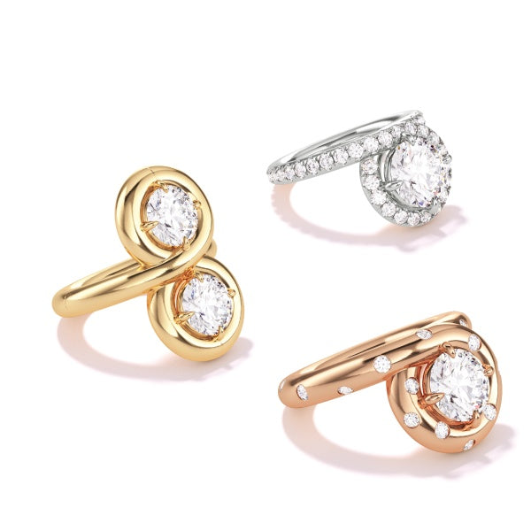 Collection of rings including a two-stone loop yellow gold ring, a platinum ring with pavé diamonds, and a rose gold ring.