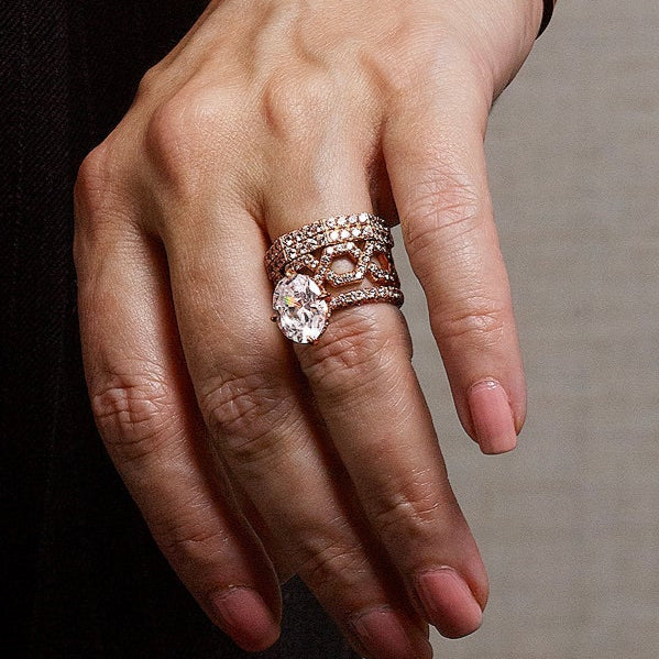 Close-up shot of rose gold diamond rings and pavé wedding bands stacked beautifully on a woman’s ring finger.