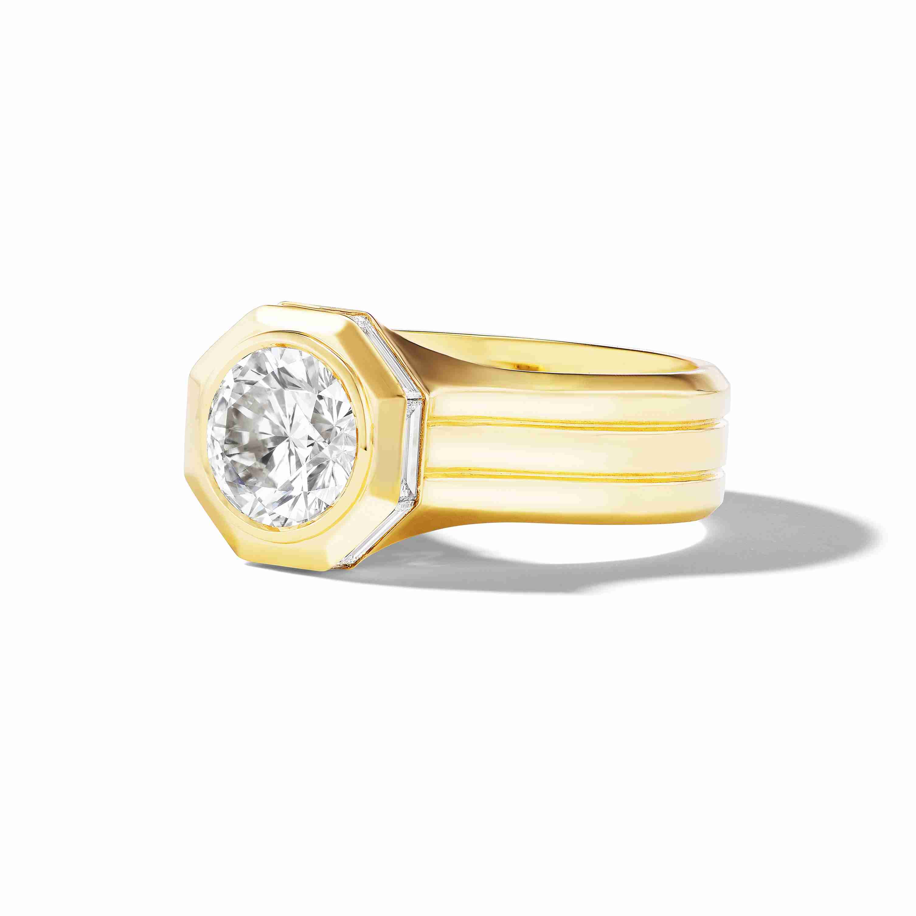 Close-up of a yellow gold ring with a wide shank and an octagonal-cut diamond set at the center.