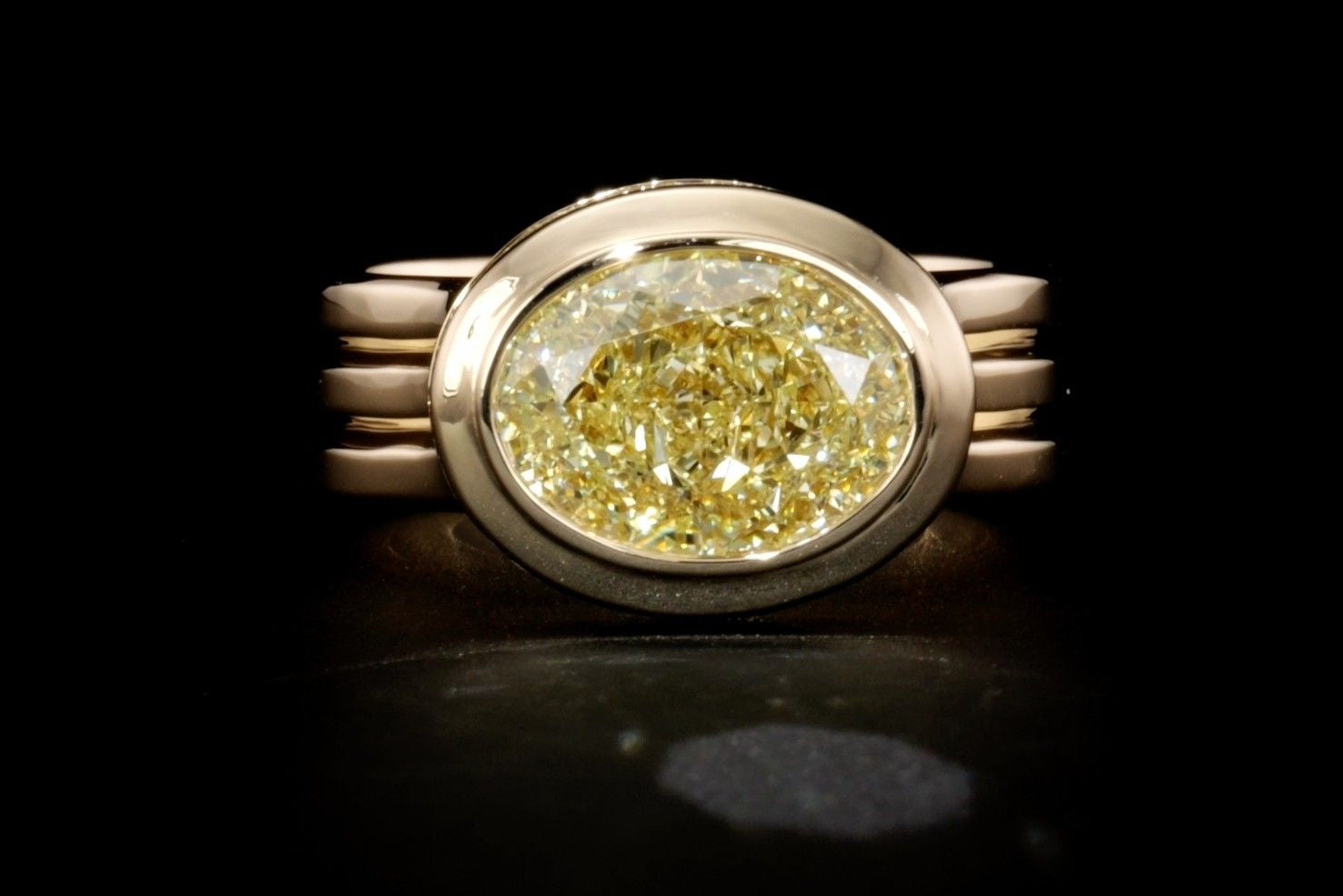 Close-up front view of a yellow gold engagement ring with a yellow oval-cut diamond.