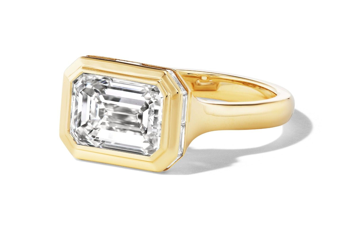 Emerald-cut diamond ring in yellow gold shown from an angled view.