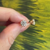 A hand holding round diamond stud earrings featuring a custom crown setting.