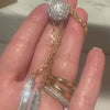 A hand holding a two-toned gold and platinum diamond lariat necklace with star detail.