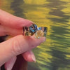 A hand holding a wide band toi et moi ring with a yellow diamond and grey spinel by Lindsey Scoggins Studio.