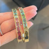 Hand displaying bespoke custom Note to Self collection gold bangles, featuring scattered rubies and diamonds with a subtle rainbow effect.