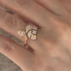 Close-up of a woman's hand wearing a rose gold leaf-shaped diamond ring with an open wrap design.