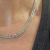 Close-up of a woman wearing a platinum diamond necklace with alternating round and baguette diamonds.