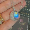 A hand holding the Moonstone and Diamond Necklace featuring a pavé diamond crescent moon from the Celestial collection.
