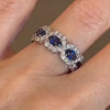 A hand wearing a wide Chance collection band with blue sapphires and intersecting diamond rows.