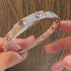 A person holding a Bezel Set Pink Sapphire and Diamond Bangle by Lindsey Scoggins Studio.