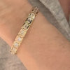 Woman’s hand wearing a yellow gold bracelet set with emerald-cut diamonds along the band.