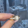 A hand holding a thick gold men's ring with a round diamond in an octagon bezel by Lindsey Scoggins Studio.