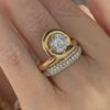 A hand wearing an Endless Loop gold ring with a diamond solitaire.