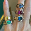 Bespoke Gypsy link rings from Lindsey Scoggins Studio’s Oath collection with vibrant green, blue, and pink gemstones, modeled on a hand.