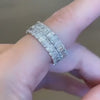 Hand displaying a custom bridal stack of round and emerald cut diamond bands.