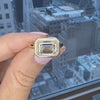 Hand displaying a custom east-west bezel set diamond ring against a city skyline.