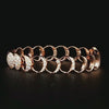 Close-up of a custom rose gold Moon Phase Bracelet on a dark background.