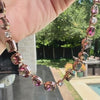 A hand holding a necklace with mixed-cut bi-color tourmalines and diamonds.